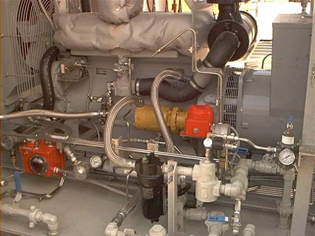 Close-up view of industrial machinery with pipes, valves, gauges, and a large motor inside a mechanical room.