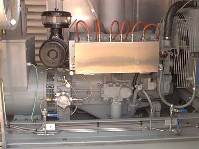 A close-up view of industrial machinery showing pipes, wires, and various metal components in a mechanical setting.